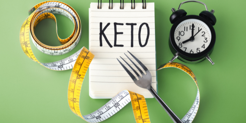 30-day-keto diet menu- the image having measurement tape, spoon, watch & written Keto in a notebook.